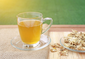 Chrysanthemum juice in glass cup and dried Chrysanthemum flower on wood background.