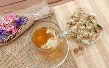 Chrysanthemum juice in glass cup and dried Chrysanthemum flower on wood background.