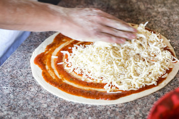 Close up of hands of chef baker preparing pizza at kitchen. Selective focus.