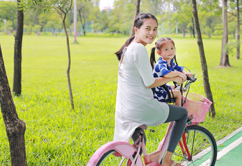 Family outdoor activity. Asian mother and her child girl on a bike at the park in the morning.

