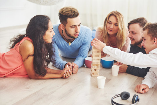 Group of creative friends sitting at wooden table. People having fun while playing board game
