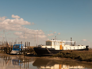 parked moored white and black boat in dockland marshland
