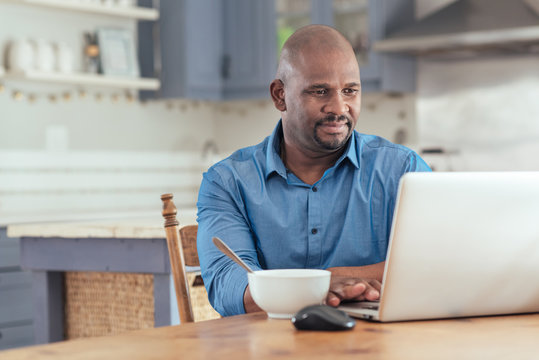 Mature African man using a laptop over breakfast