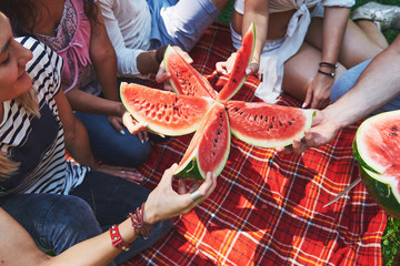 Cheerful friends enjoying watermelon on picnic on sunny summer day - obrazy, fototapety, plakaty