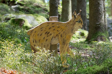 Education in the forest - wooden lynx waiting to be spotted by children