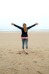 Young woman watching the sea in autumn with hands up