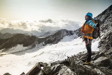 Wall murals Mountaineering Winner/Success concept. Climber enjoying a view from the mountain top after climbing the exposed rocky and snowy mountain