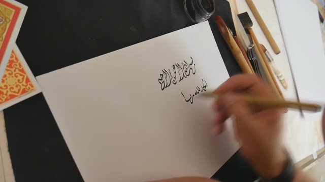 Arabic calligraphy. The calligrapher writes ink on paper.