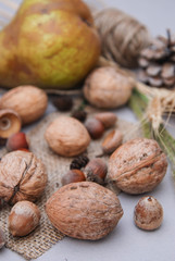 Autumn composition with nuts, pears and dry leaves on rustic background