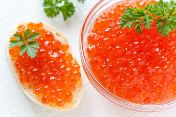 Red salmon caviar in glassware on a white wooden background