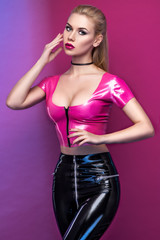 Fashion studio portrait of beautiful stylish blond touching head on pink gradient background