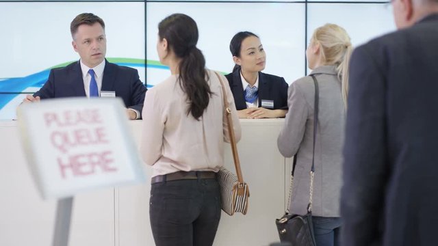  Friendly bank workers assisting queue of customers with enquiries
