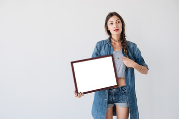 Fototapeta premium Girl showing to an empty frame