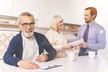 Obraz premium Positive aged man signing papers