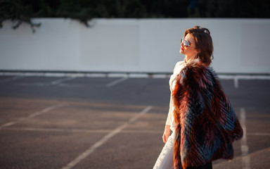 elegant brunette in sunglasses and mink coat walking in the street