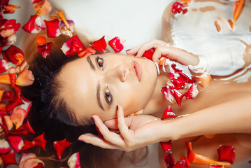 Obraz na płótnie Canvas beautiful sexy brunette lying in the bathroom with rose petals