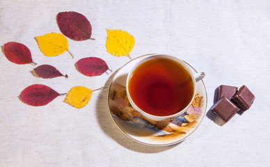 Autumn tea. A cup of tea with chocolate and autumn leaves. View from above.