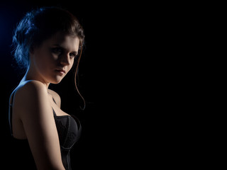 beautiful sad young woman on black background with copy space looking at camera