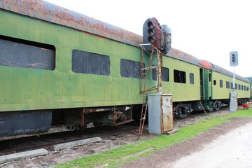 Obraz premium Green abandoned passenger train cars with boarded windows beside light posts on train tracks 