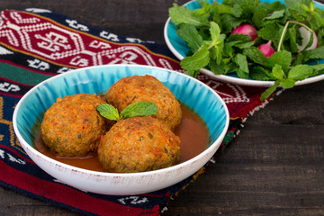 Koofteh Tabrizi Large Meatballs Stuffed With Dried Fruits, Berries And Nuts In Tomato Turmeric Broth A Traditional Azeri And Iranian Dish Served In Turquoise Bowl and Herbs