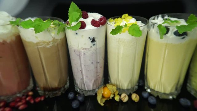 Glasses with delicious milk shakes with whipped cream,  ice-cream cocktails with berries and mint leaves on dark  background