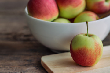 Fuji apple on cutting board put on rustic wood table and stack in white bowl with copy space.Delicious sweet and juicy fuji apple suitable for salad cooking or bakery. Fuji apple has origins in Japan.