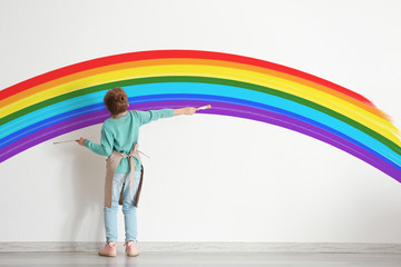 Cute little girl painting on wall in empty room