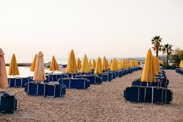 Yellow umbrellas and beach chairs at the at Aegean Sea beach. Start of season concept