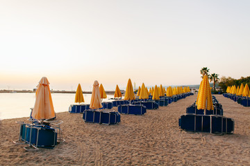 Yellow umbrellas and beach chairs at the at Aegean Sea beach. Start of season concept