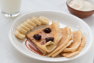 Thin pancakes with butter and honey on white plate, vertical
