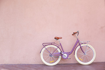 Stylish new bicycle near color wall outdoors