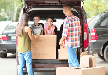 Happy family with boxes near car, outdoors