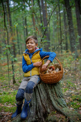 Cute boy with wild mushroom found in the forest