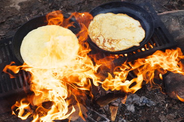 Russian pancakes are fried on the fire during the Maslenitsa Carnival