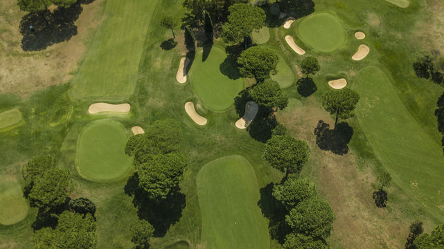Vista aerea panoramica di un vasto campo da golf presso un circolo sportivo immerso nel verde. Si notano le buche con gli ostacoli per raggiungerle.