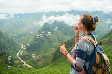 traveller woman blowing soap bubbles in mountains.