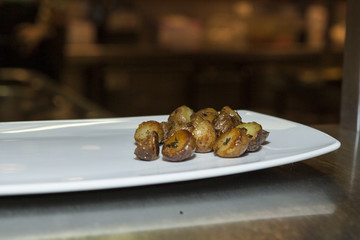 Boiled and fried in oil with parsley, dill and various spices potatoes. Potatoes on a white porcelain plate on the table
