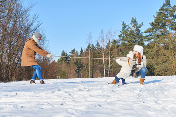 Familie mit Kind beim tauziehen im Schnee