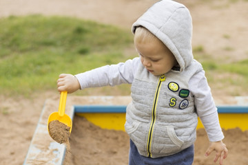 Cute baby boy playing wuth sand on the children playground