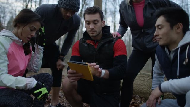 Group of runners on a run in the woods using computer tablet for navigation.