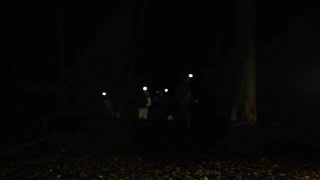 Group running in the woods at night wearing lamps on headgear.