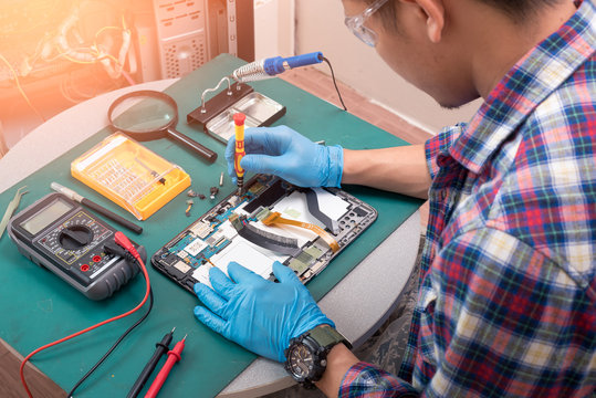 The abstract image of the asian technician repairing a tablet by screwdriver in the lab. the concept of computer hardware, mobile phone, electronic, repairing, upgrade and technology.