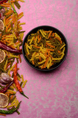 delicious colorful italian pasta, plate and ingredients on textured background