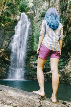 Traveler woman looking at waterfall in summer.