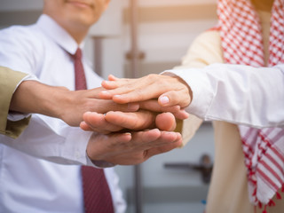 Engineer, arab businessman stacking hands express their teamwork and cooperation