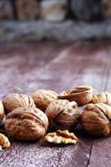 Walnut kernels and whole walnuts on rustic old wooden table.