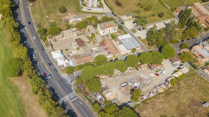 Vista aerea di una strada di periferia della cipitale d' Italia, Roma. Ci sono poche auto sull'asfalto e pochi sono anche gli edifici intorno, i quali sono costruiti in mezzo al verde.
