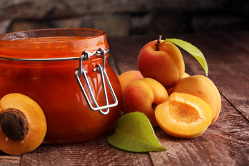 Jam from apricots in a glass jar on a wooden surface
