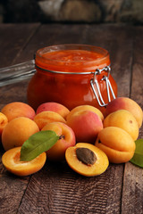 Jam from apricots in a glass jar on a wooden surface