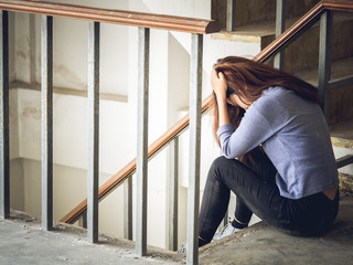 Young woman feeling upset, disappointed, bad, broken heart, stressed sitting alone on stair crying